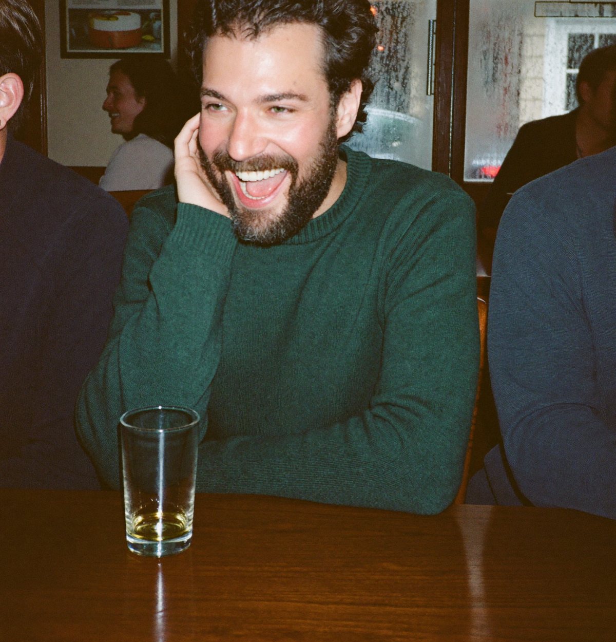 A man laughing with friends at a pub table