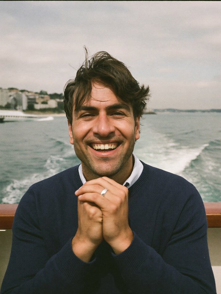 A man on a ferry deck looking into the camera with an open smile