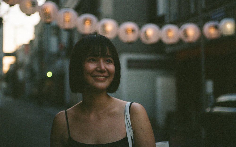 A woman walking under paper lanterns on an evening street